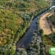 Rio com meandro entre floresta densa e campos agrícolas, vista aérea.