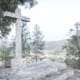 Cruz de granito em pedra num miradouro com vista para vale e eucaliptos