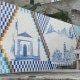 Painel de azulejos decorativo com motivo xadrez azul e branco, ilustrando uma capela e paisagem montanhosa em tons de azul.