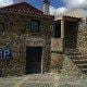 Edifício de pedra com telhado de telha, porta de entrada e sinal de parque de estacionamento.