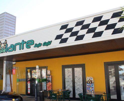 Fachada do Volante Sport Café com painel solar xadrez e fundo amarelo