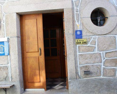 Porta de madeira aberta em fachada de pedra com sinais de