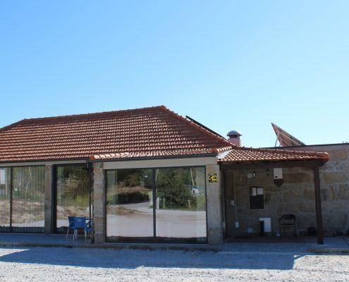 Fachada de restaurante com telhas vermelhas, grandes janelas e zona de esplanada coberta