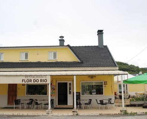 Fachada amarela do Restaurante Flor do Rio com esplanada e guarda-sol verde