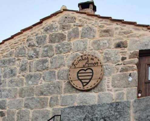 Fachada de pedra com emblema circular de coração e texto no topo