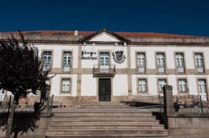 Edifício de arquitetura neoclássica com fachada branca e pedra, dois pisos, escadaria central e brasão municipal.