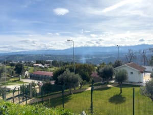 Propriedade rural com edifícios, campos vedados e vista panorâmica de vale montanhoso.